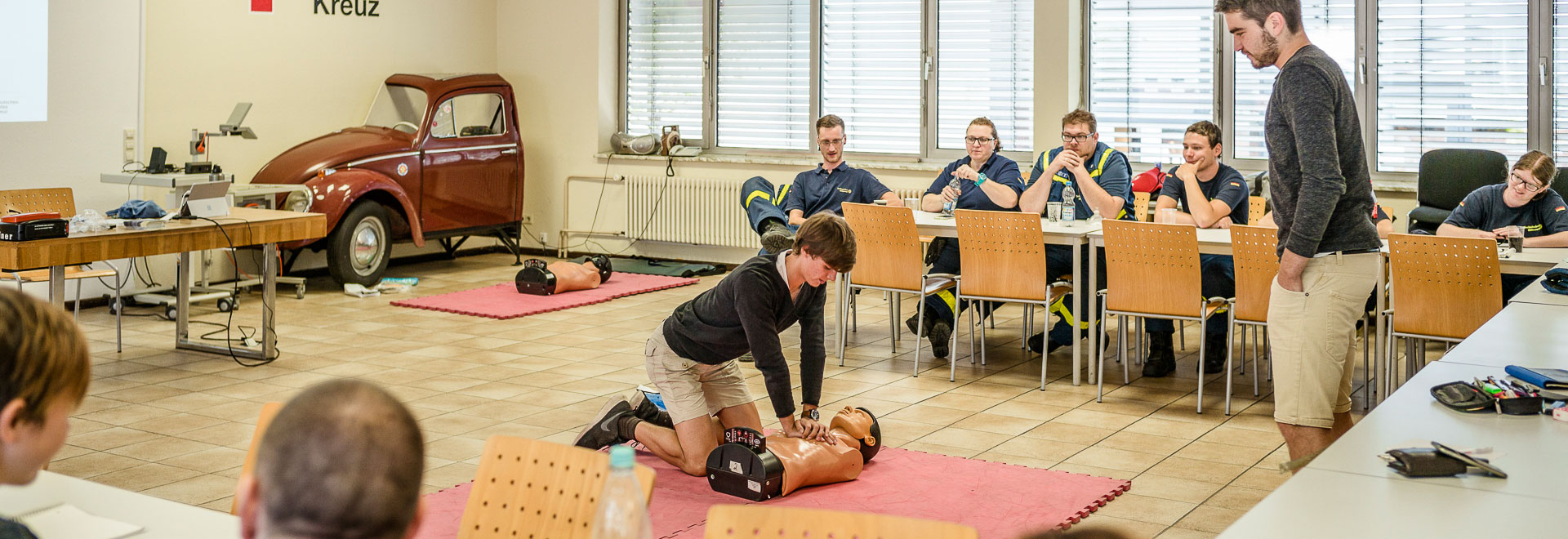 Rotkreuzkurs: Junger Mann übt Herzmassage an einer Puppe