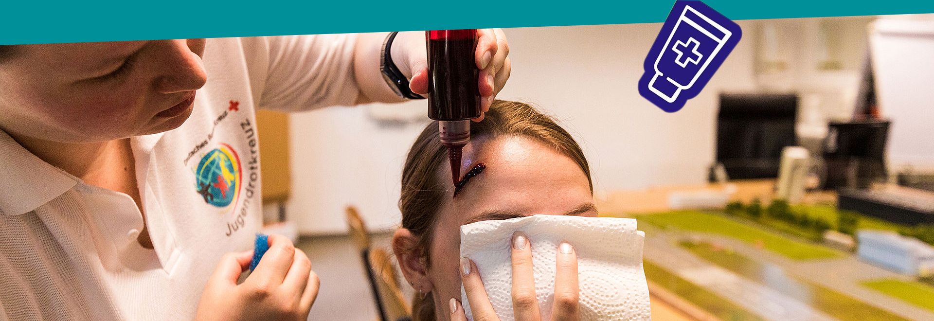 Eine junge Frau schminkt einem Mädchen eine Wunde auf die Stirn