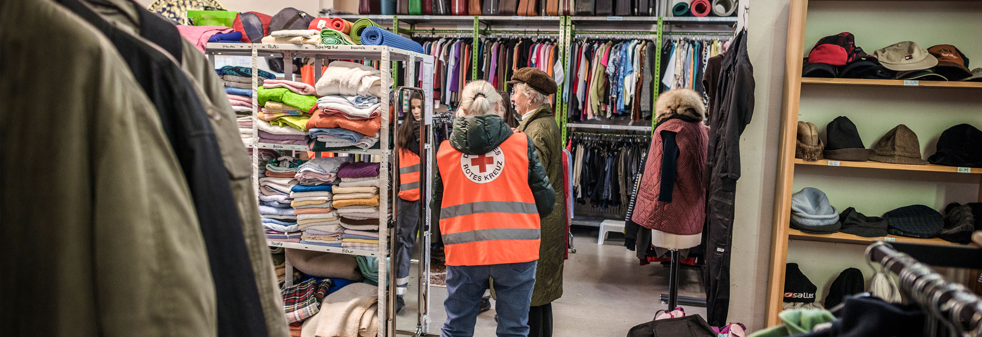 DRK-Mitarbeiter und eine Kundin im Kleiderladen