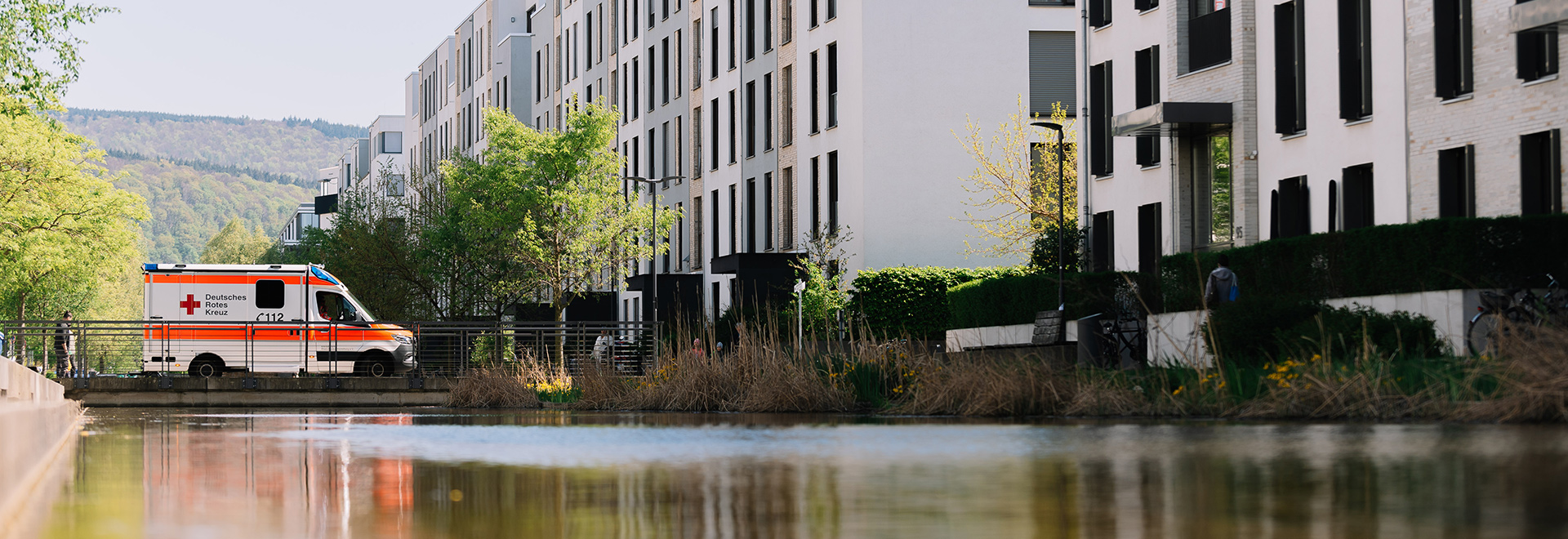 Rettungswagen fährt über eine Brücke zu großen Gebäuden