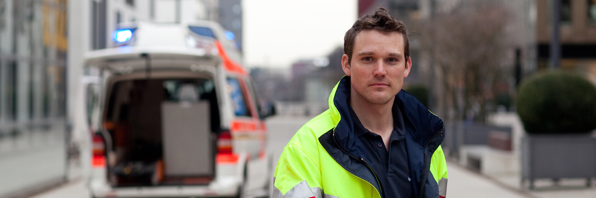 DRK-Mitarbeiter bei einem Krankentransport-Fahrzeug