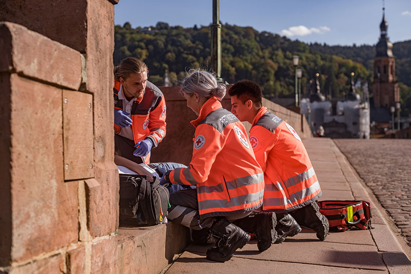 Drei Rettungssanitäter versorgen einen verletzten auf einer Brücke