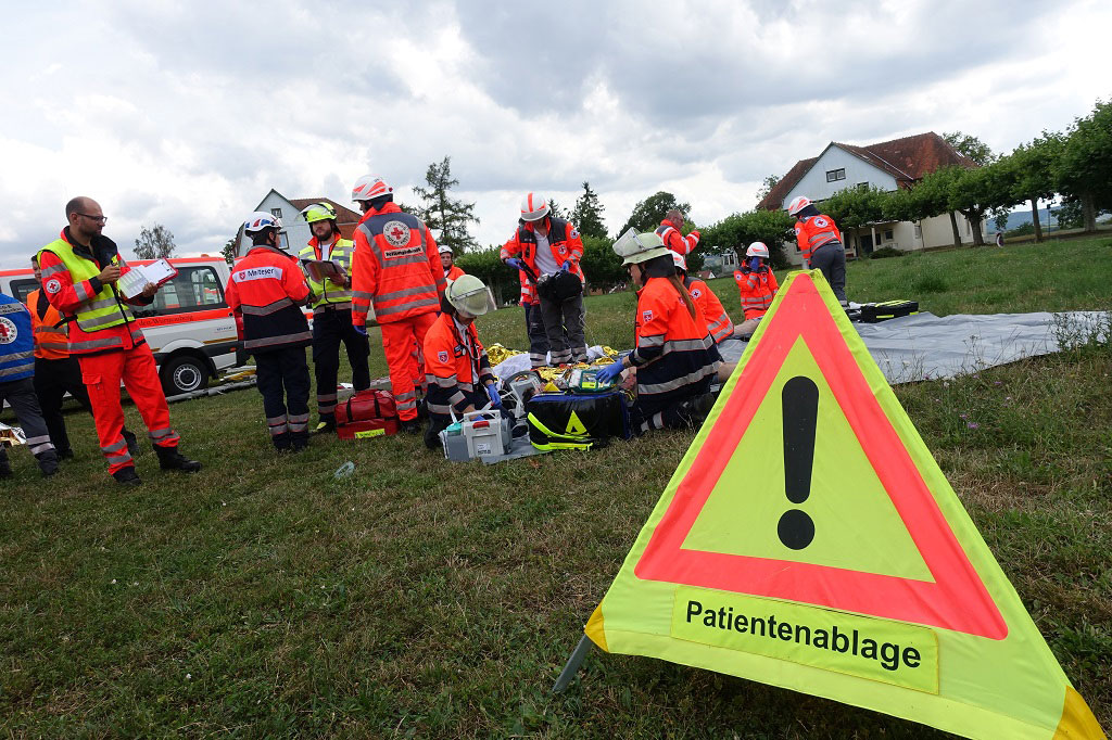 Warndreieck Patientenablage und Rettungskräfte auf einer Wiese