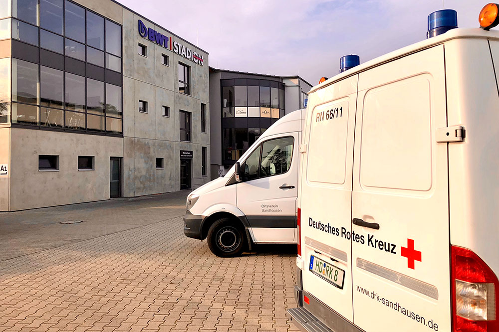 Zwei DRK-Fahrzeuge vor einer Halle