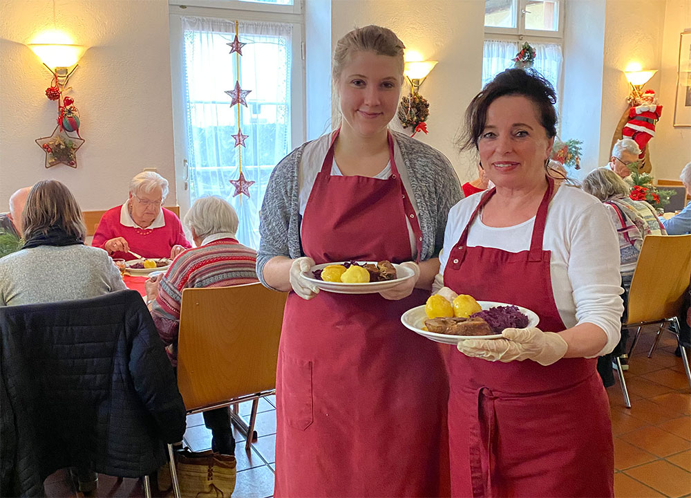 Zwei Damen halten jeweils einen Teller mit Gans, Klößen und Rotkraut