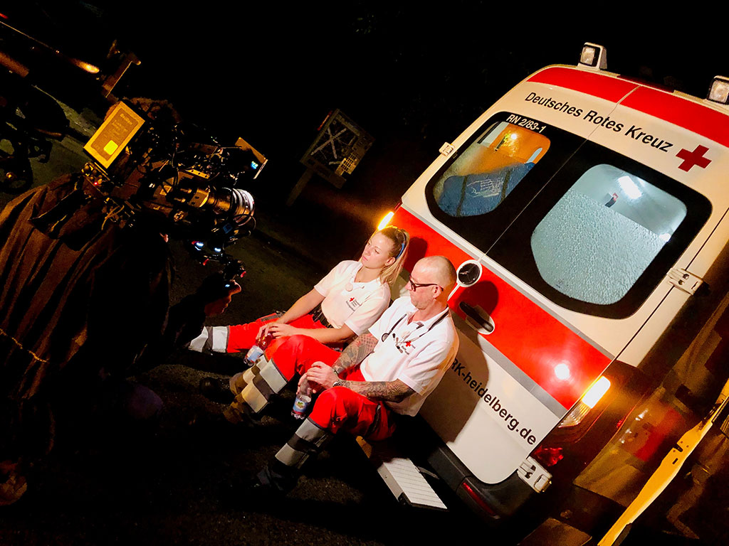 Zwei Notfallsanitäter am Rettungswagen werden gefilmt