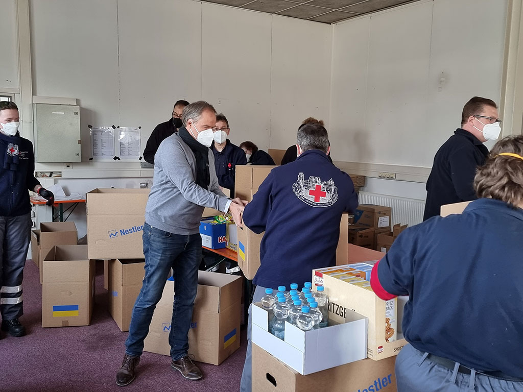 Dr. Eckart Würzner, Oberbürgermeister Stadt Heidelberg, und DRK-Mitarbeiter packen Care-Pakete