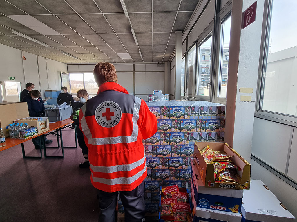 DRK-Mitarbeiter koordinieren die Verteilung der gespendeten Produkte für die Care-Pakete