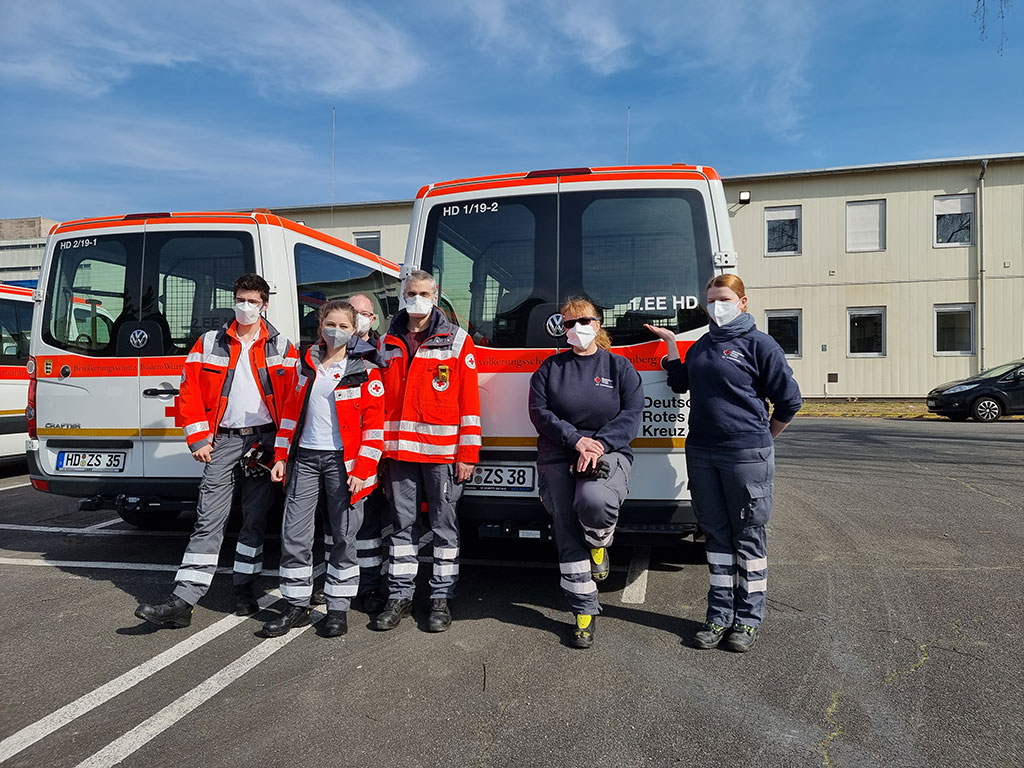 Gruppe von Ehrenamtlichen Helfern vor DRK-Fahrzeugen