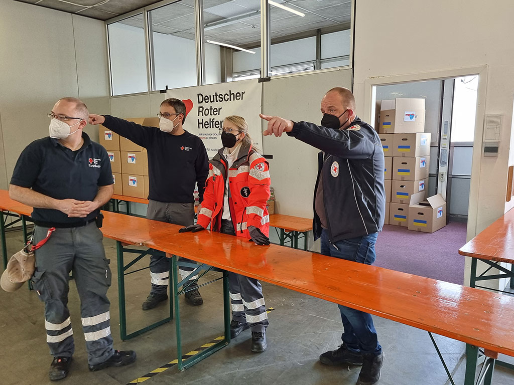 DRK-Mitarbeiter bereiten Tische für eine Ausgabestelle vor