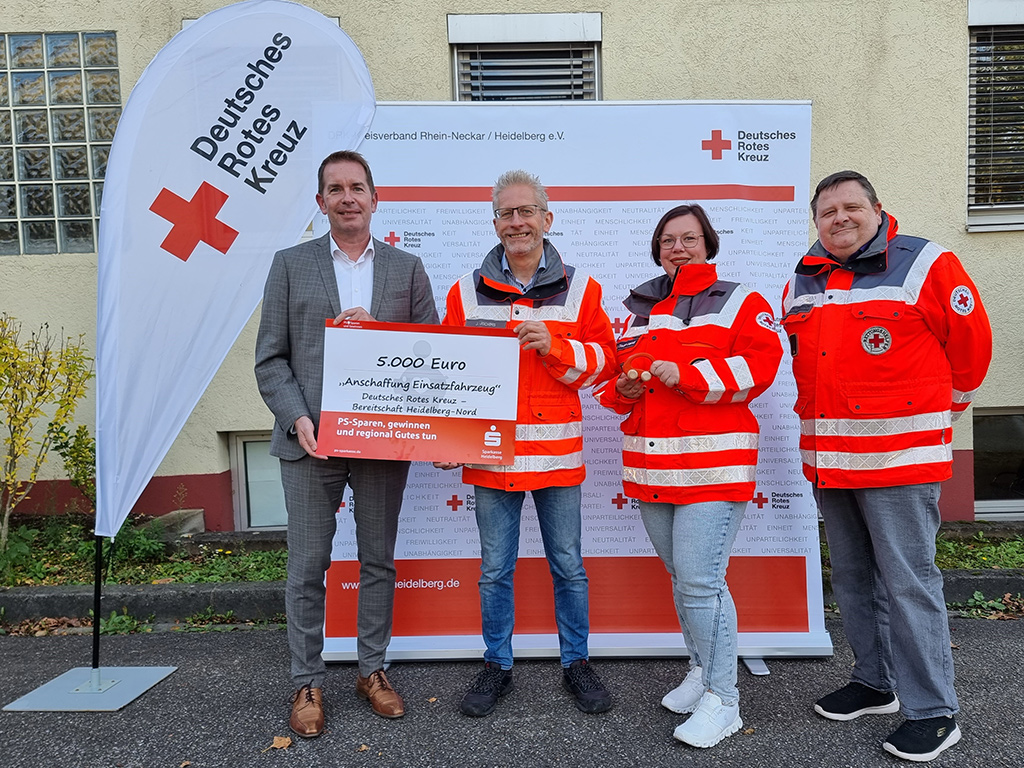 Sparkassenbereichsleiter Markus Fissl, sowie Jürgen Jochims, Anne-Sophie Stadler-Heindl und Claus Gutfleisch von der DRK-Bereitschaft Heidelberg Nord freuen sich über die erfolgreiche Anschubfinanzierung eines neuen Einsatzfahrzeugs.