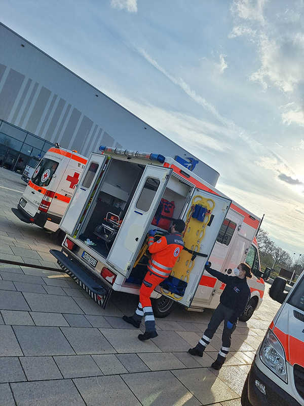 DRK-Mitarbeiter an ihren Fahrzeugen vor dem SNP-Dome