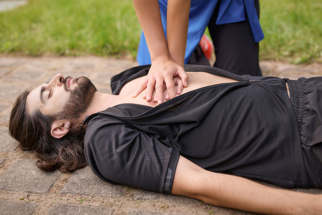 Jemand macht bei einem Mann eine Wiederbelebung durch Herzmassage