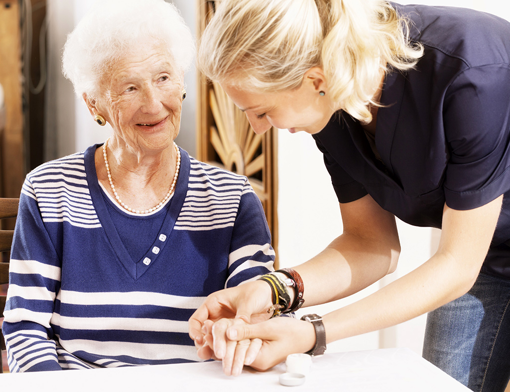 DRK-Mitarbeiterin massiert die Hand einer Seniorin