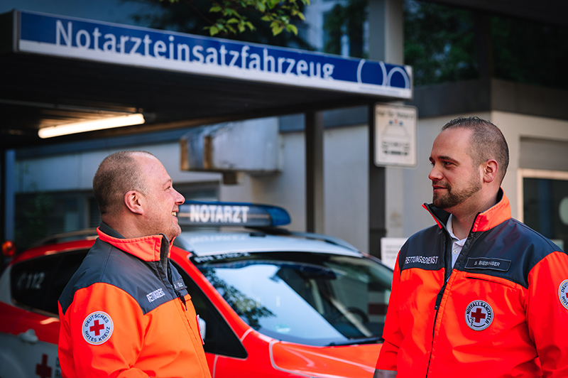 Zwei DRK-Mitarbeiter unterhalten sich vor einem Gebäude