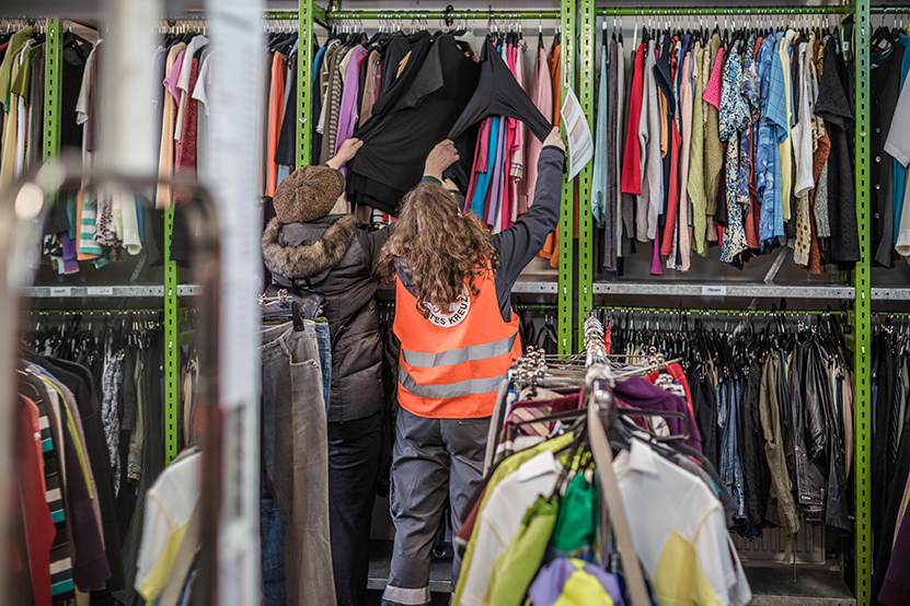 Eine Mitarbeiterin berät eine Kundin im Kleiderladen