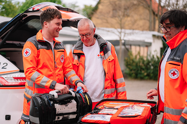 Drei DRK-Mitarbeiter unterhalten sich fröhlich