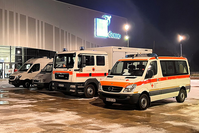 DRK-Rettungswagen am Abend auf einem Parkplatz vor einer Halle
