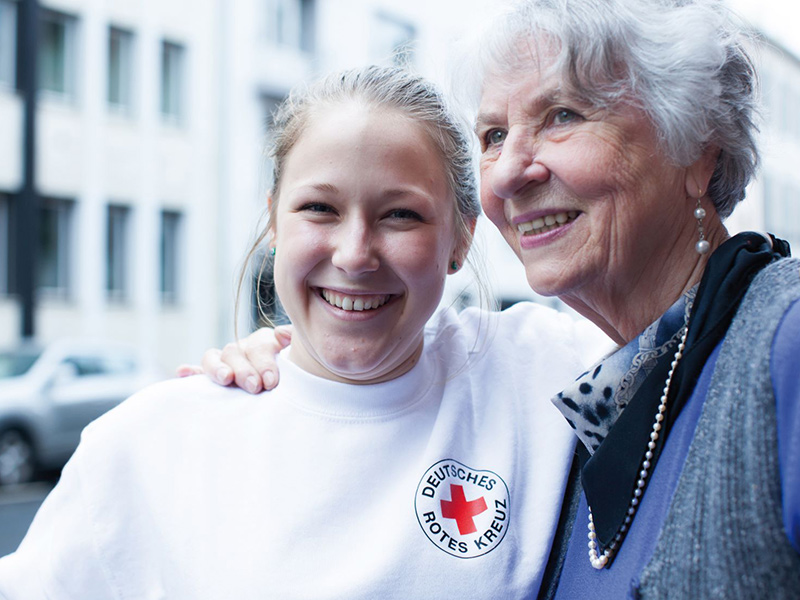 Zwei DRK-Mitarbeiter begleiten einen Rollstuhlfahrer