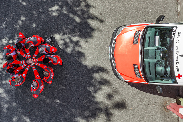 DRK-Team im Kreis fassen sich im Mittelpunkt an den Händen